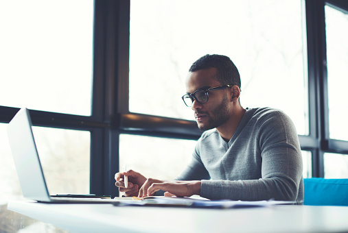 A man smiling and looking at the laptop while filling the forms.